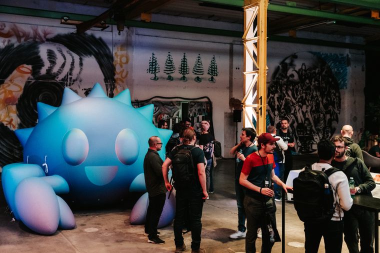 People standing together in groups at EuroRust in conversations, a big, ca. 3min tall, inflatable Ferris in the background